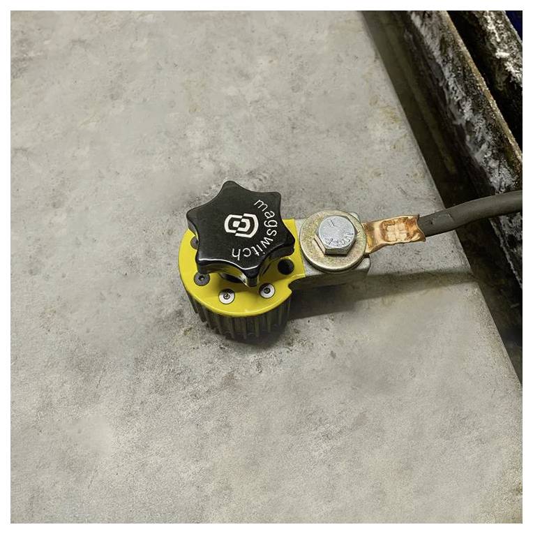 Un commutateur industriel de gaz jaune et noir est monté sur une surface en ciment avec un fil métallique connecté et un boulon pour la fixation.