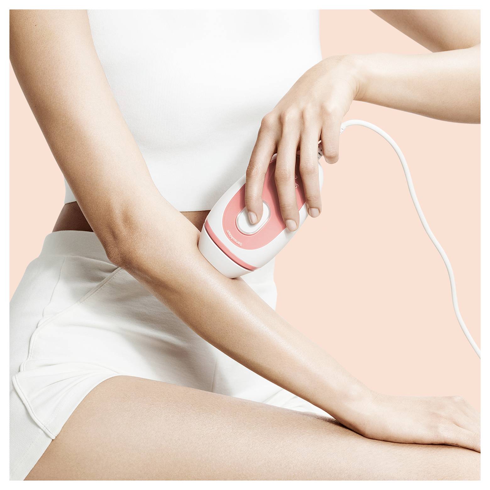 Une personne utilise un appareil portable sur son avant-bras pour un traitement de soin de la peau ou de beauté, illustrant une technologie simple d'utilisation à domicile.