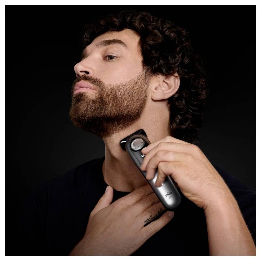 Une personne taille sa barbe avec un rasoir électrique, en se concentrant sur la zone du cou, dans un plan rapproché.