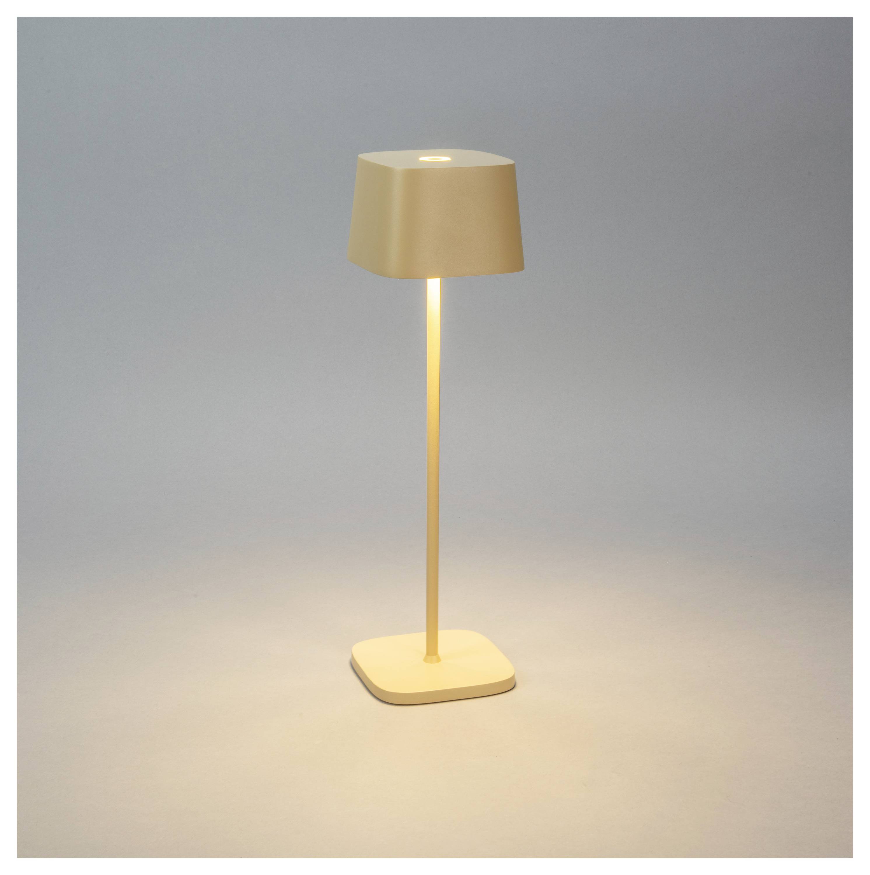 Un lampadaire élégant et moderne avec une finition beige, doté d'une base carrée et d'un abat-jour carré, diffuse une lumière chaleureuse dans un environnement minimaliste.