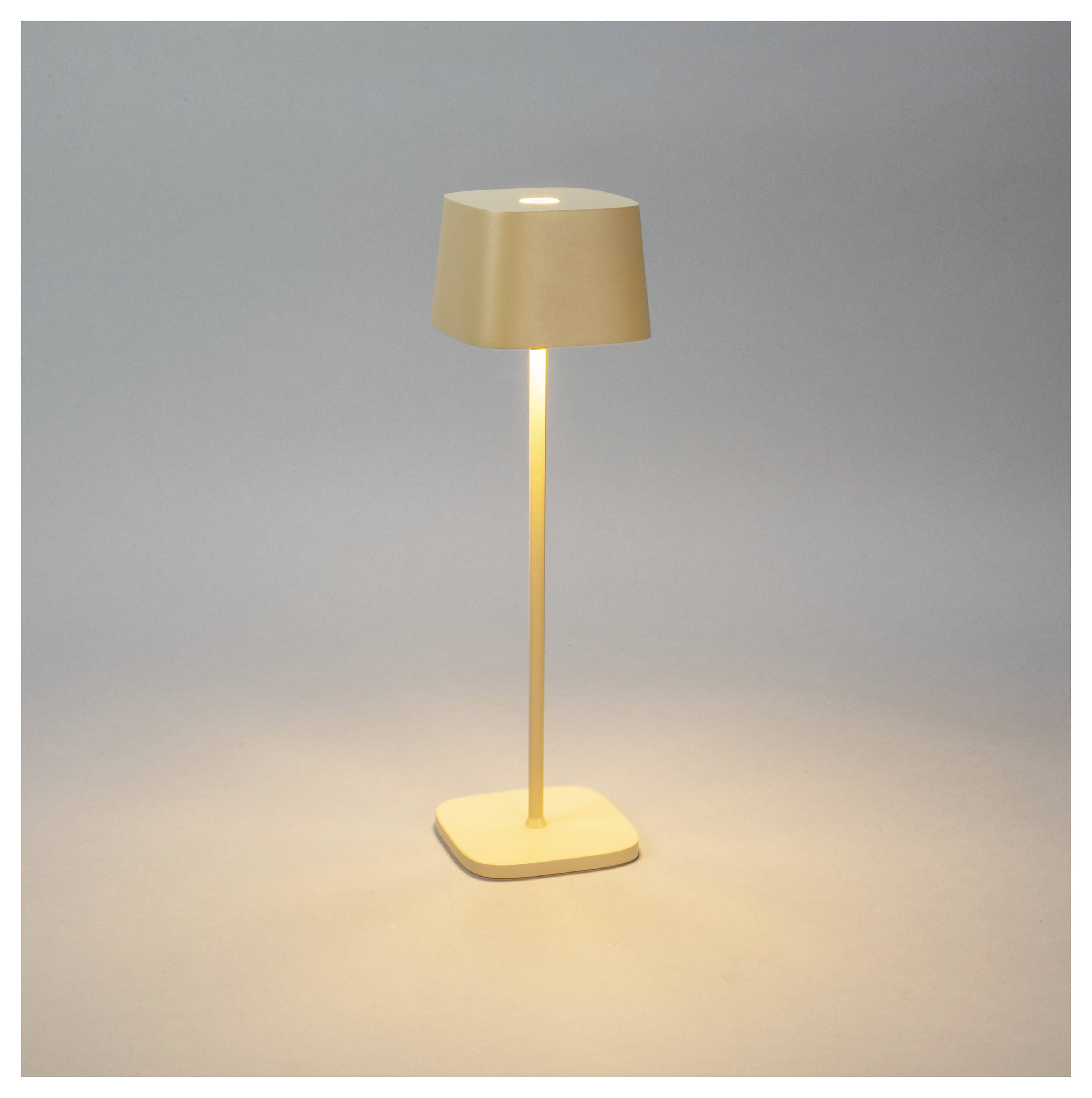 Une lampe élégante et moderne de couleur beige, avec un abat-jour et un socle carrés, diffusant une lumière douce sur un fond neutre.