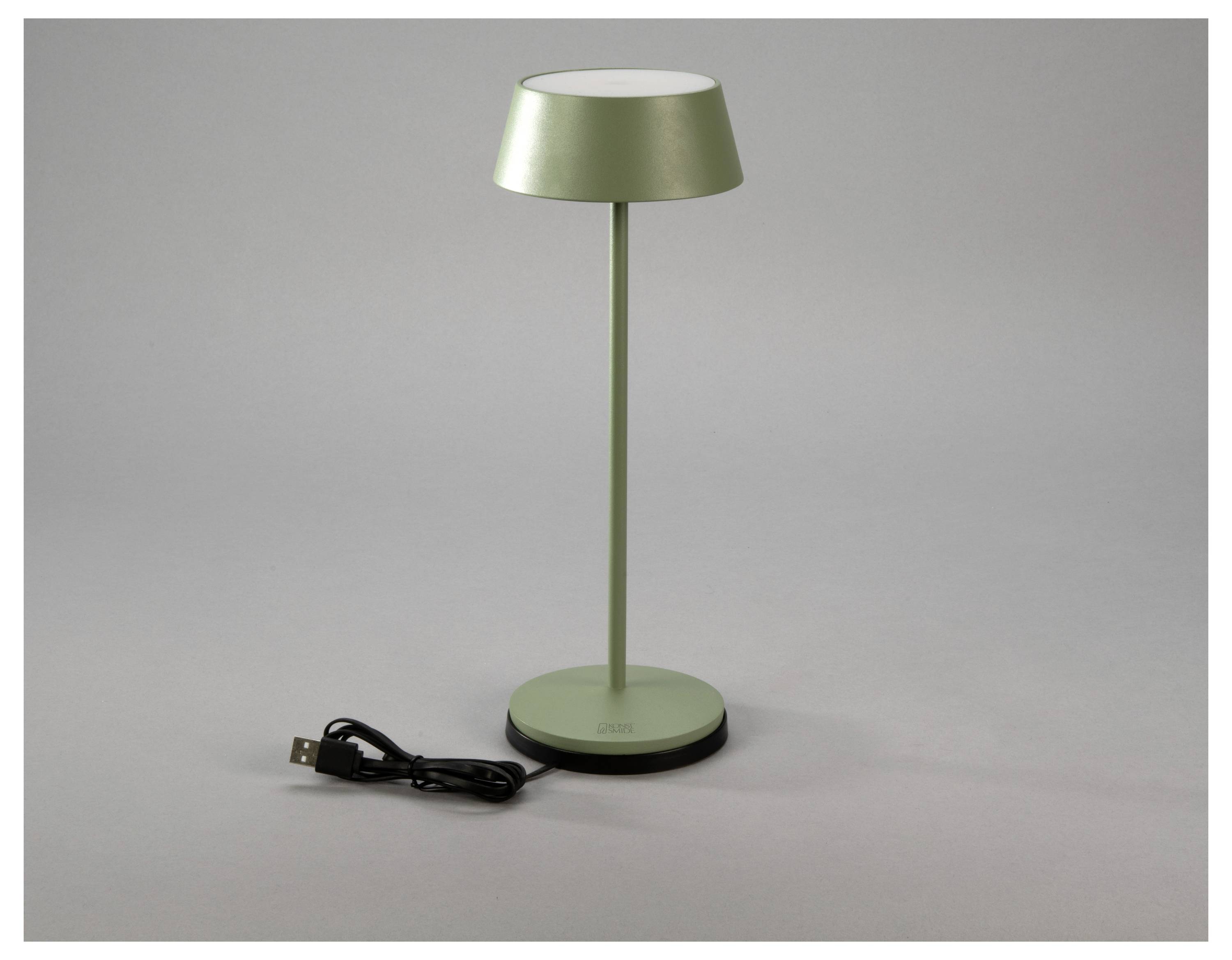 Une lampe de bureau verte au design minimaliste, accompagnée d'un câble de chargement USB, posée sur un fond gris neutre.