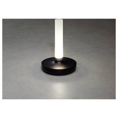Une lampe de table moderne, cylindrique, diffuse une lumière blanche douce à travers une colonne en verre dépoli, posée sur une base circulaire simple et noire, contre une surface grise.