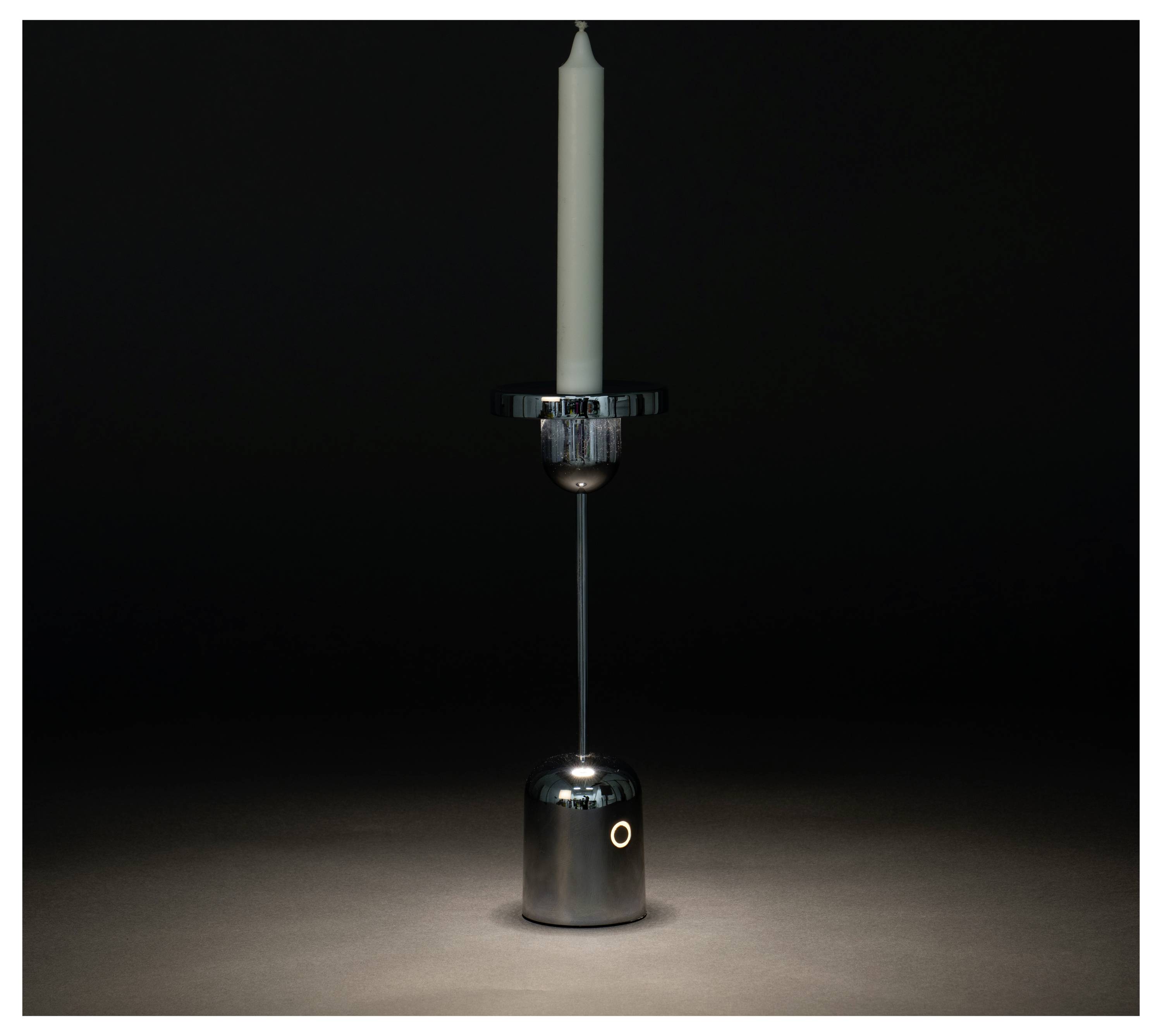 Un support de bougie élégant en argent avec une bougie blanche haute se dresse dans une lumière tamisée, offrant une apparence minimaliste et moderne.