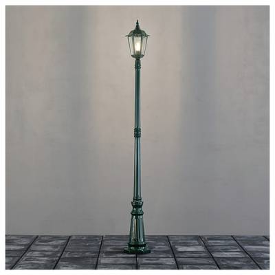 Un lampadaire vintage solitaire avec une lumière douce, dressé sur un chemin pavé de galets contre un fond uni.