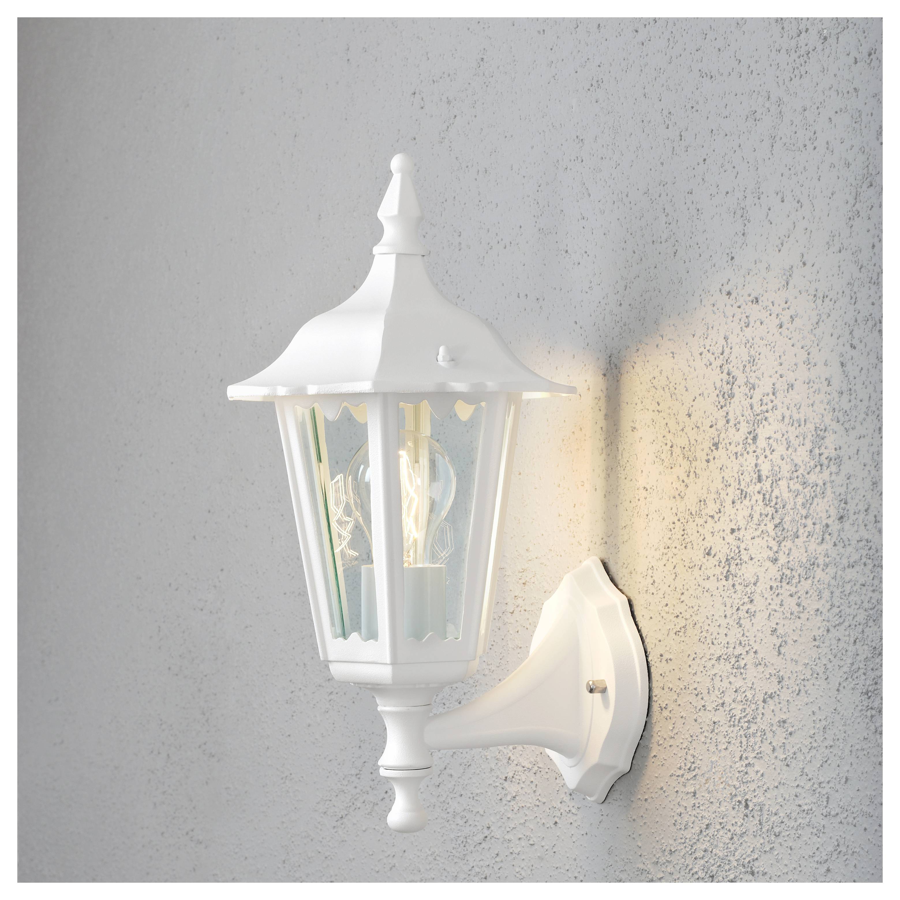 Une lanterne extérieure blanche au design classique, montée sur un mur texturé, s'illumine doucement, diffusant une lueur subtile.