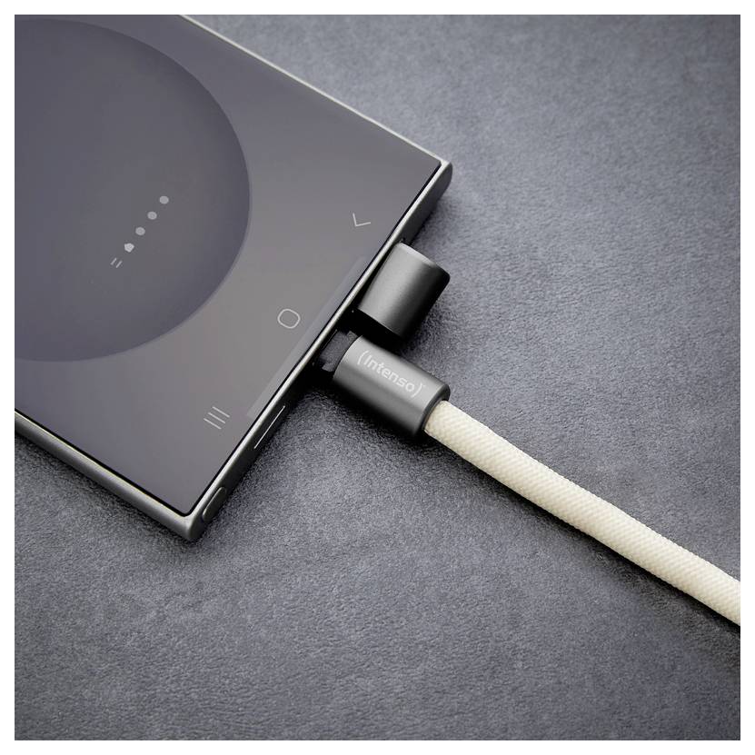 Un smartphone connecté à un câble de charge beige sur une surface sombre. L'écran du téléphone affiche une icône de batterie partiellement chargée.