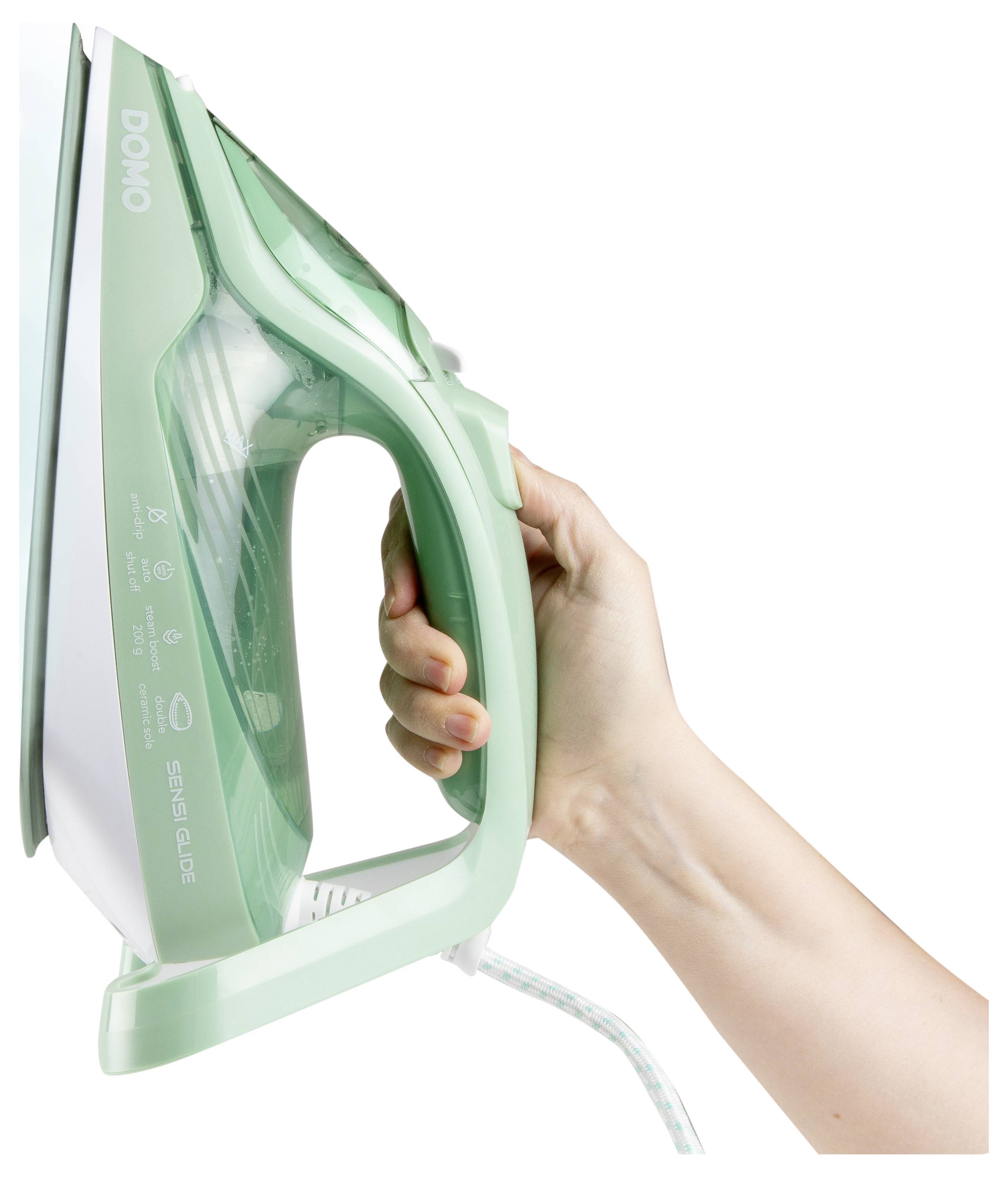 Une main serre un fer à vapeur vert et blanc. Le fer est tenu horizontalement, révélant les détails de la marque et du modèle sur le côté.