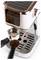 Machine à espresso avec des touches de cuivre, montrant un porte-filtre et une cuillère de café moulu, posée sur un plateau égouttoir en métal.