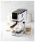 Une machine à espresso domestique préparant du café dans une tasse, avec du lait et du sucre à proximité, un verre de latte sur le côté, et un biscuit en arrière-plan.