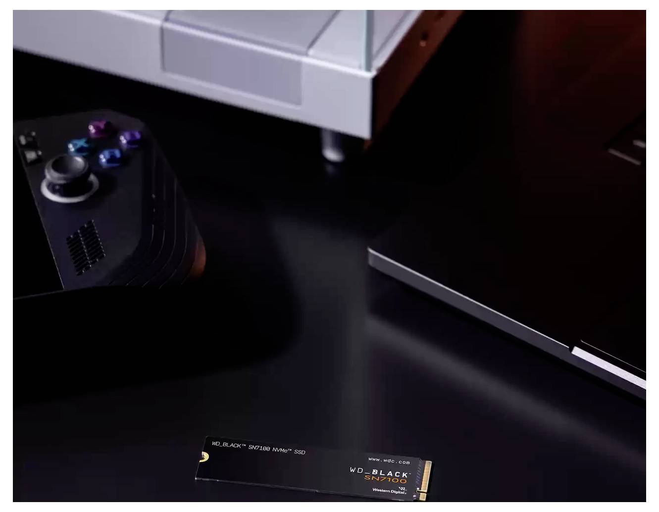 Un gros plan d'une console de jeux, un ordinateur portable noir et un SSD WD_BLACK SN770 sur une surface sombre, mettant en valeur la technologie de jeu.