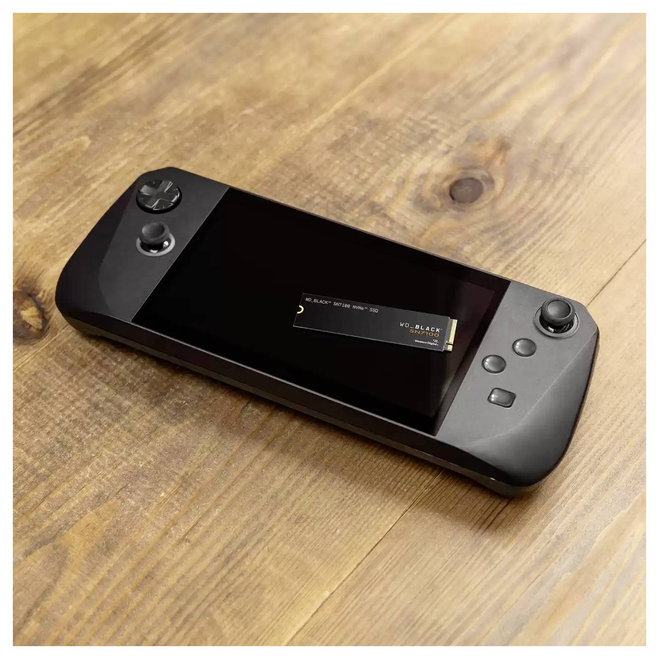 Une console de jeu portable avec un écran noir repose sur une surface en bois, affichant une carte SSD NVMe partiellement insérée.