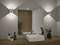 Salle de bain moderne avec un plan de travail en bois, un lavabo rectangulaire blanc, un grand miroir, des plantes, et deux appliques murales offrant un éclairage doux.