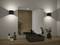 Meuble-lavabo de salle de bain moderne avec miroir rectangulaire, plan de travail en bois, évier noir, robinet et plantes en pot. Des appliques murales diffusent une lueur douce.