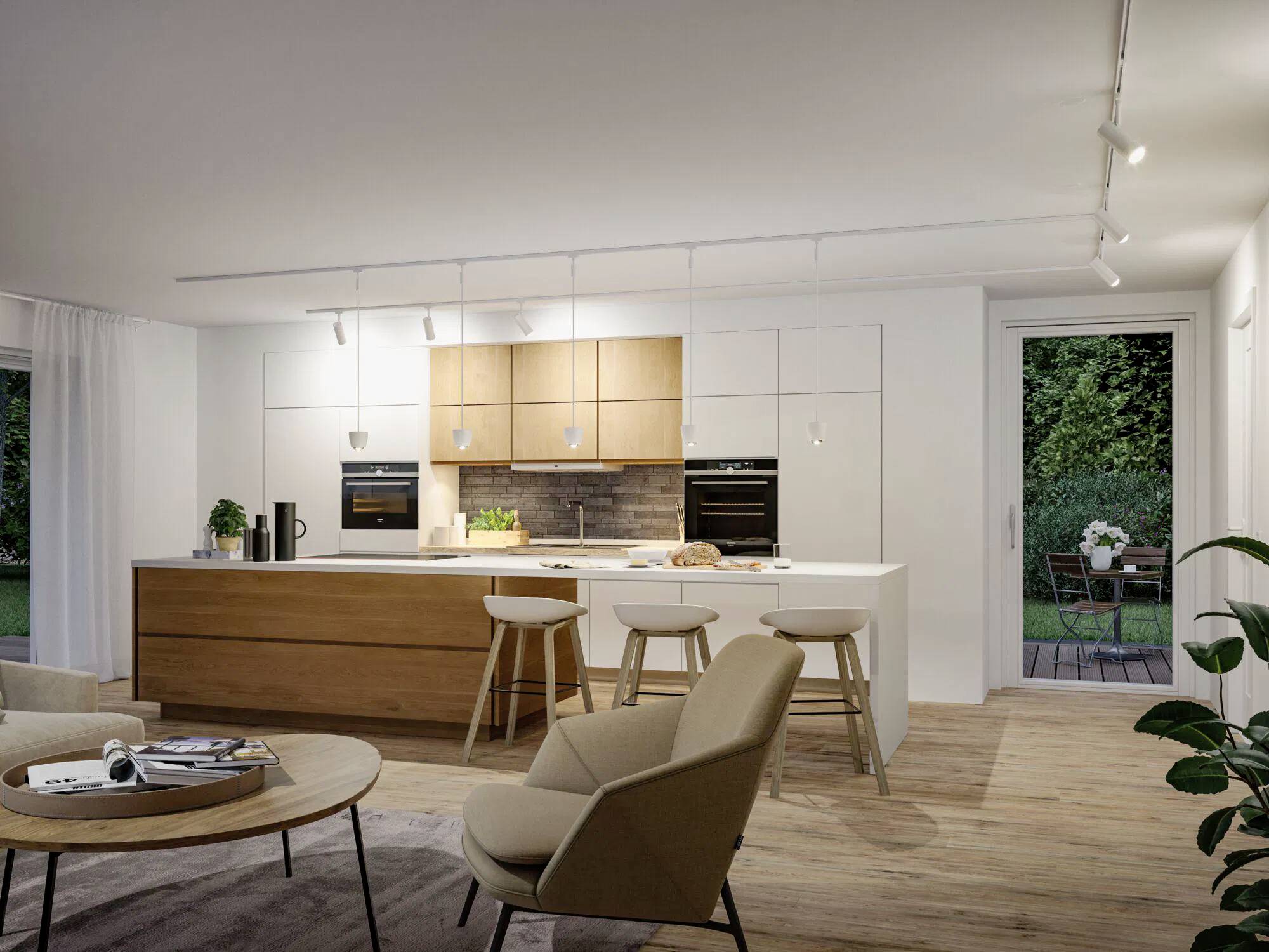 Une cuisine moderne avec un îlot central, des armoires en bois et blanches, des tabourets de bar et un éclairage sur rail. Un espace de vie douillet est adjacent, avec une terrasse visible à l'extérieur.