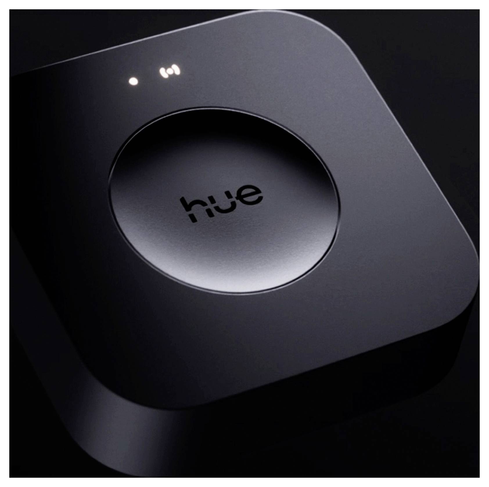 Un hub de luminaires intelligents Hue noir et élégant, doté d'un bouton central et de voyants lumineux visibles sur le dessus, utilisé pour contrôler les systèmes d'éclairage domotique.