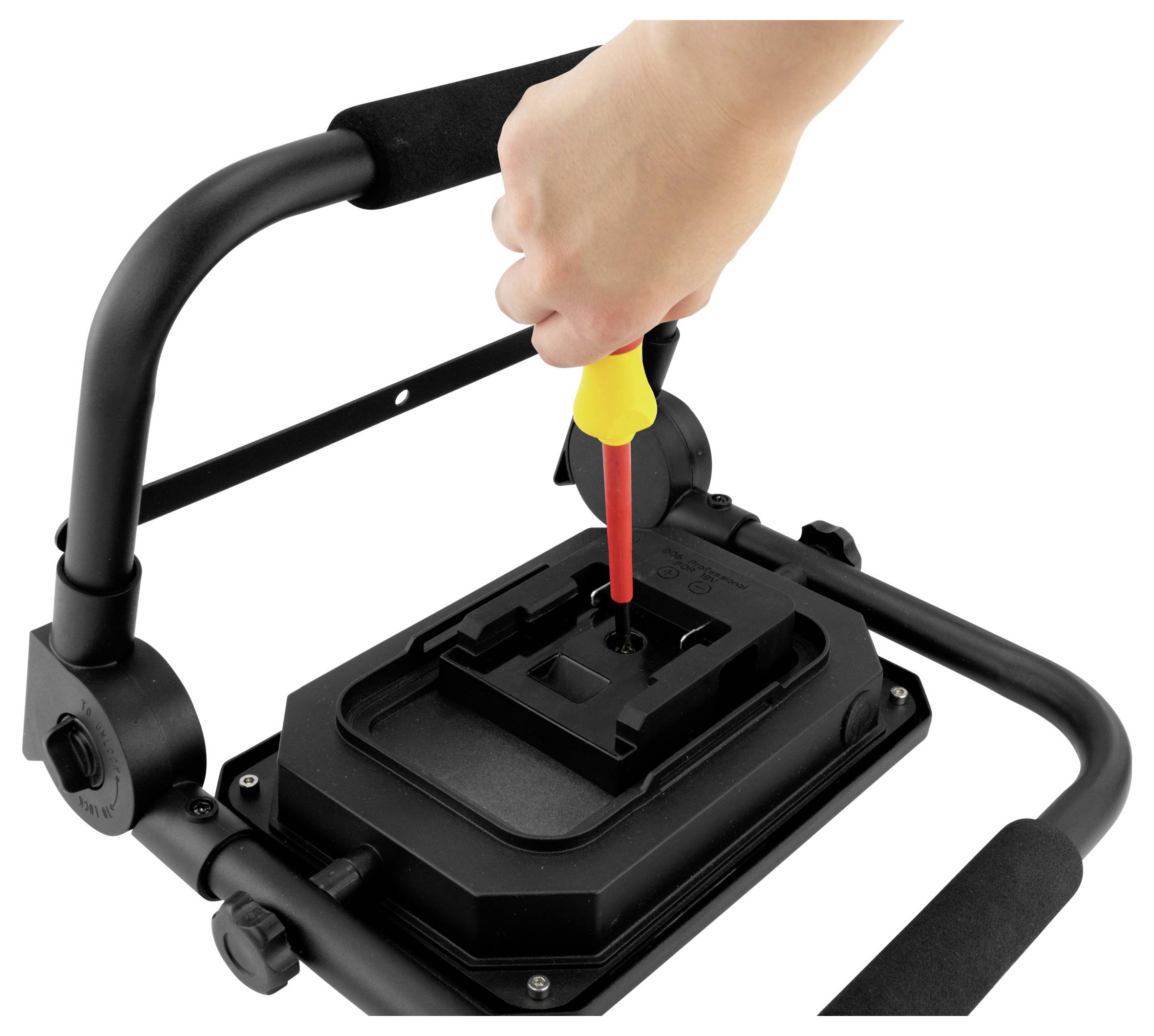 Une main utilisant un tournevis rouge pour ajuster la vis sur un dispositif noir monté sur un support à double poignée, probablement pour l'installation d'équipement vidéo.