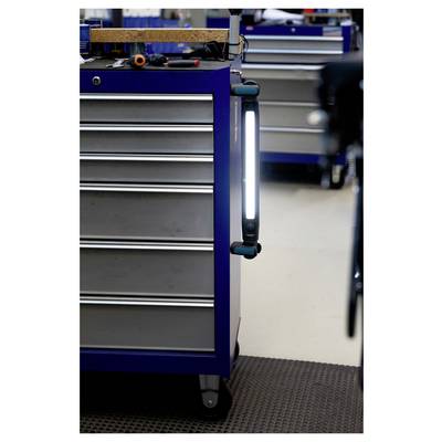 Armoire à outils bleue avec plusieurs tiroirs et un éclairage de travail magnétique fixé sur le côté ; divers outils sont placés sur le dessus.