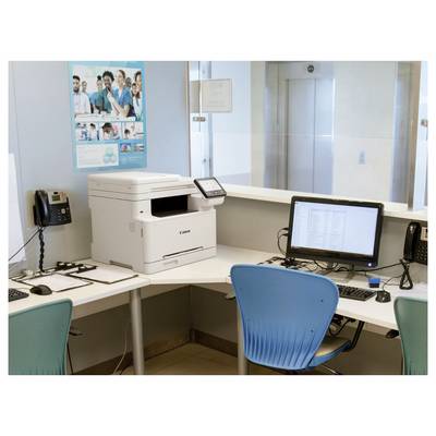 L'image montre un aménagement de bureau avec une imprimante blanche, un ordinateur avec une chaise bleue, et des téléphones sur un bureau. Des affiches sont accrochées au mur.