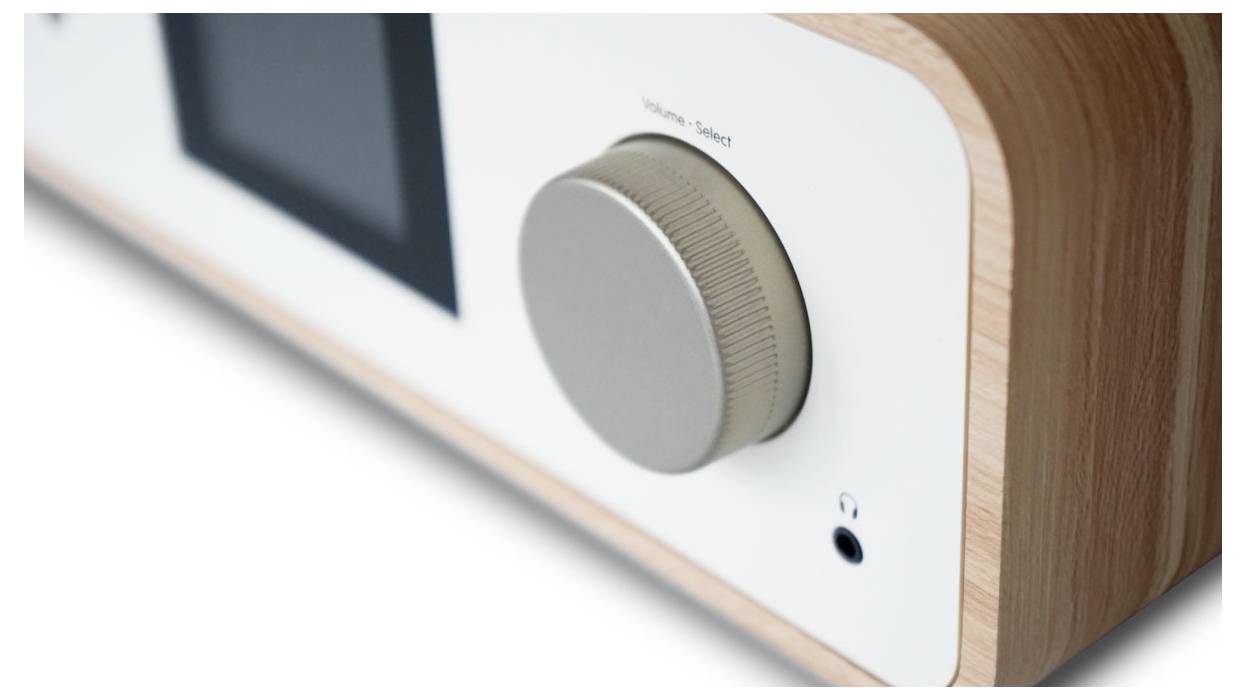 Un gros plan d'un poste de radio en bois moderne avec un grand bouton de volume et un écran.