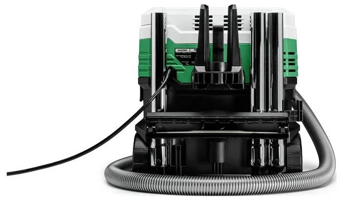 Une machine industrielle verte et noire avec des câbles et des tuyaux fixés, vue de face, sur un fond blanc.