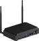 Un ordinateur noir, compact, avec un dessus strié pour la dissipation thermique, deux antennes, et plusieurs ports dont USB et Ethernet sur l'avant.