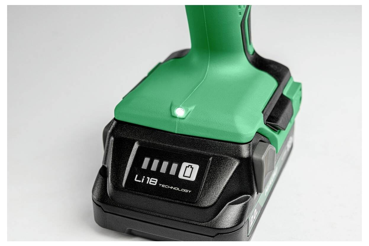 Un perforateur sans fil vert avec un indicateur de batterie Li-ion de 18V affichant une charge complète, posé sur une surface blanche.