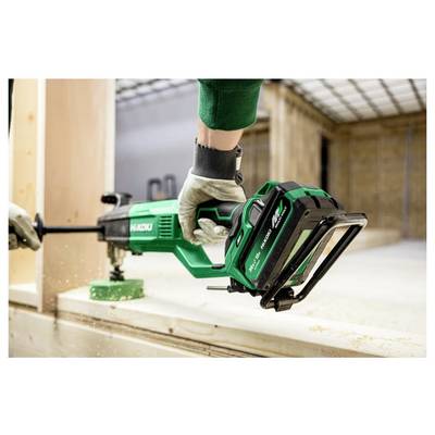 Une personne utilise une scie alternative Hikoki pour couper une planche en bois à l'intérieur, portant des gants. Des sciures sont visibles dans l'atelier dynamique.