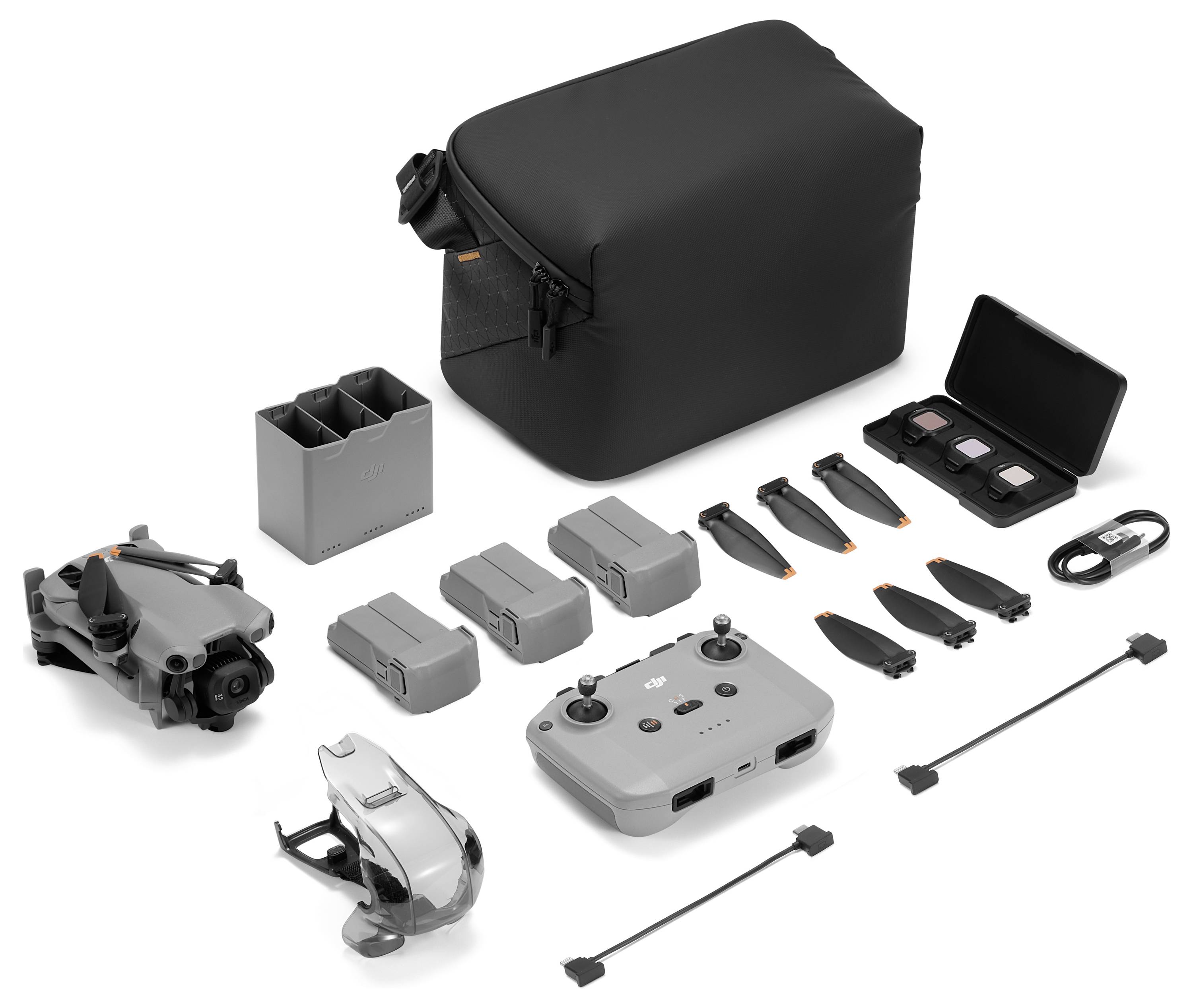 Kit de drone présenté : comprend un drone, trois batteries, une télécommande, des hélices supplémentaires, un hub de charge, des câbles et un étui de transport noir.
