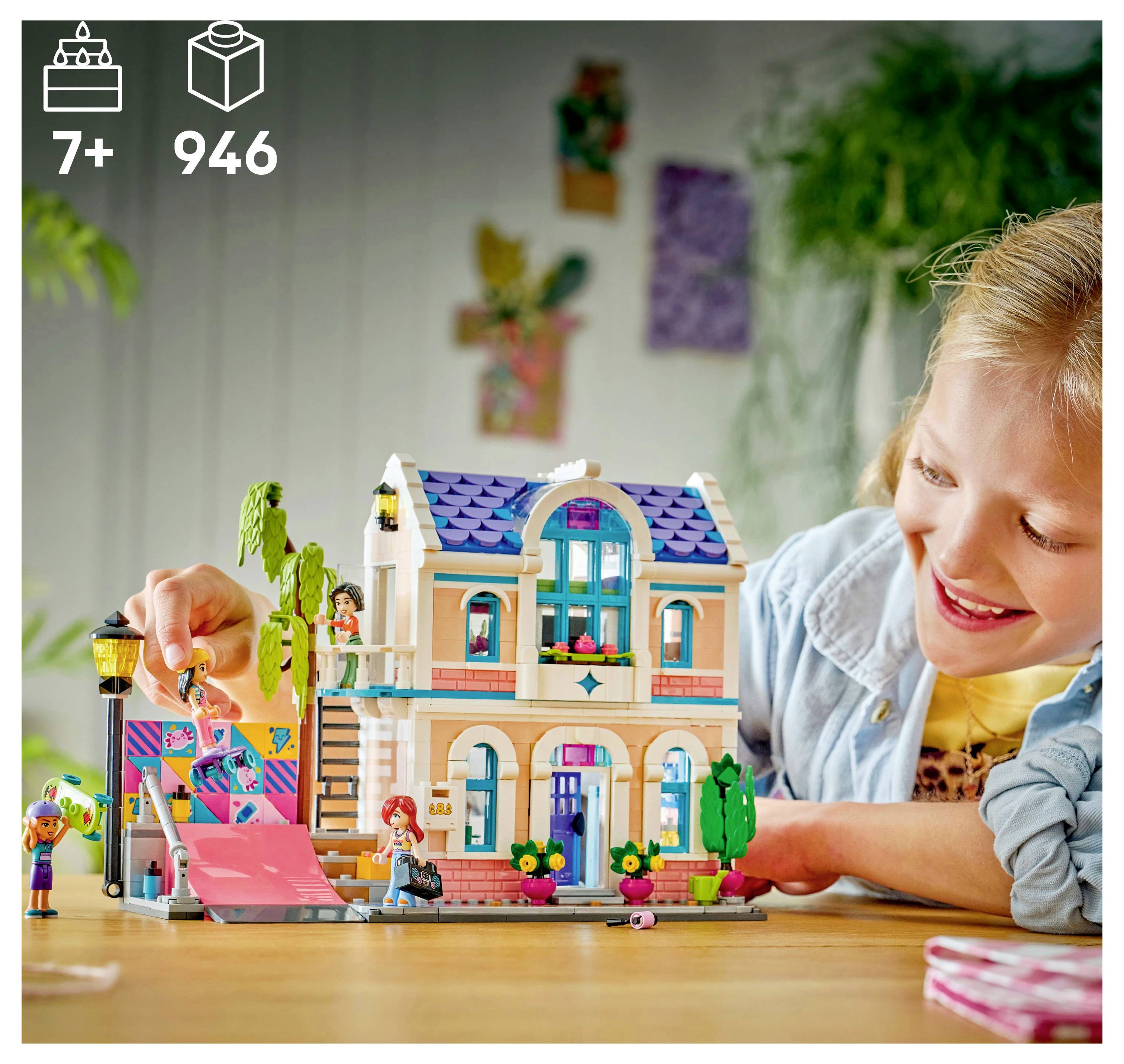 Un enfant joue joyeusement avec un ensemble de construction à deux étages, comprenant une rampe rose et de petites figurines, indiquant qu'il convient aux enfants de 7 ans et plus, avec 946 pièces.