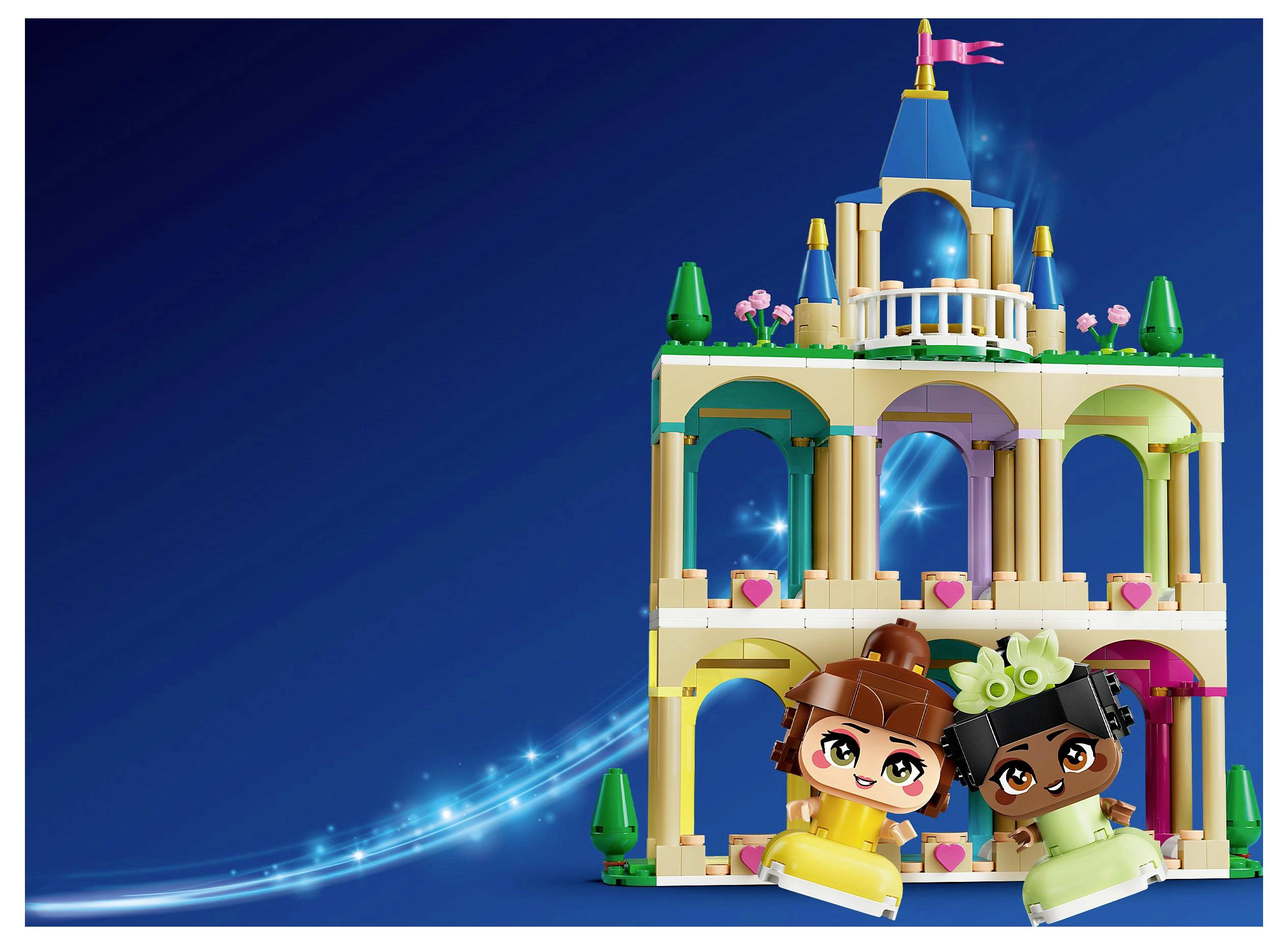 Deux figurines de jouets vêtues d'habits colorés sont assises devant un petit palais de jouet orné, avec des arches et une tour, sur un fond bleu.