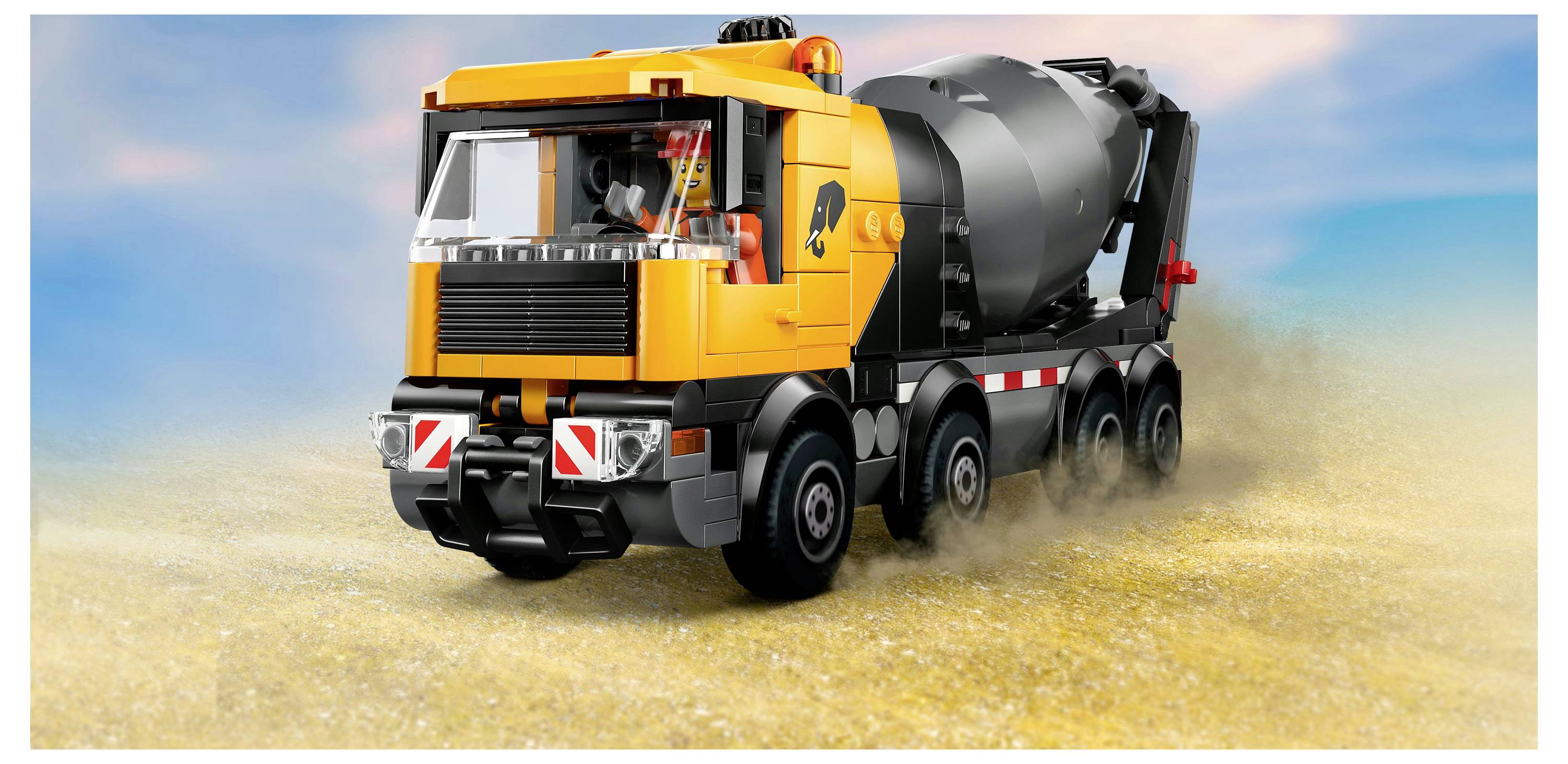 Un camion-toupie de chantier jouet jaune et noir sur une surface sableuse avec un ciel dégagé en arrière-plan.