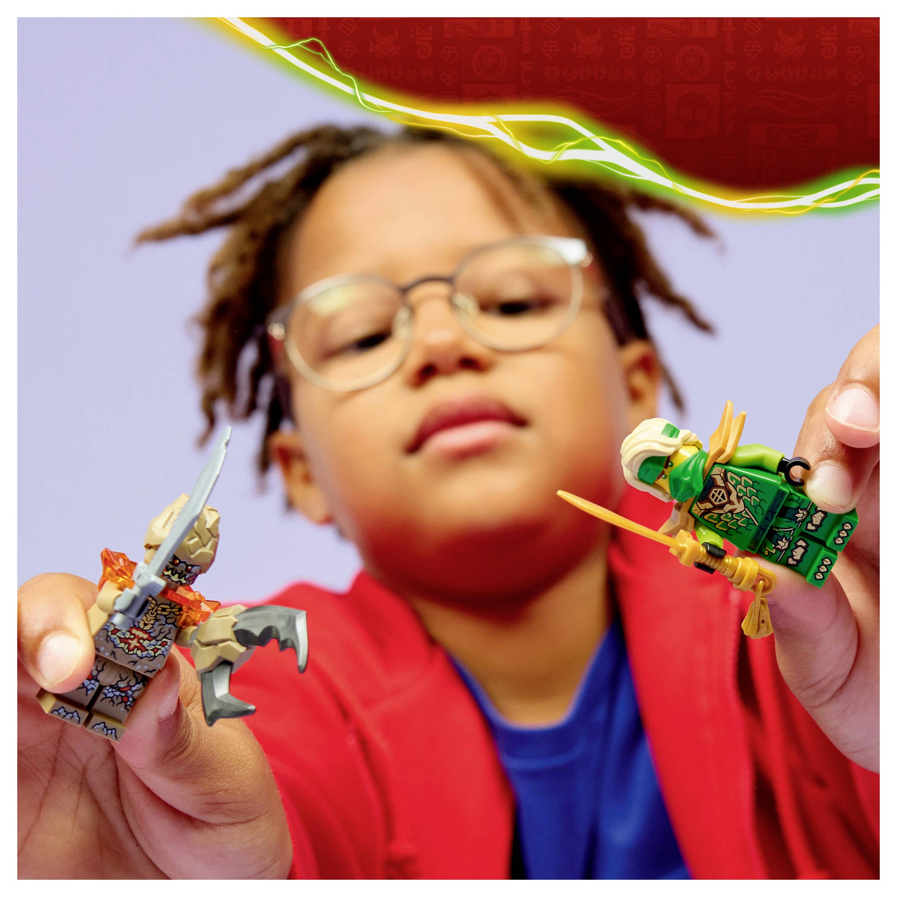 Un enfant portant des lunettes et un t-shirt rouge tient deux figurines de jouets, l'une ressemblant à un chevalier et l'autre à un ninja, devant un fond coloré.