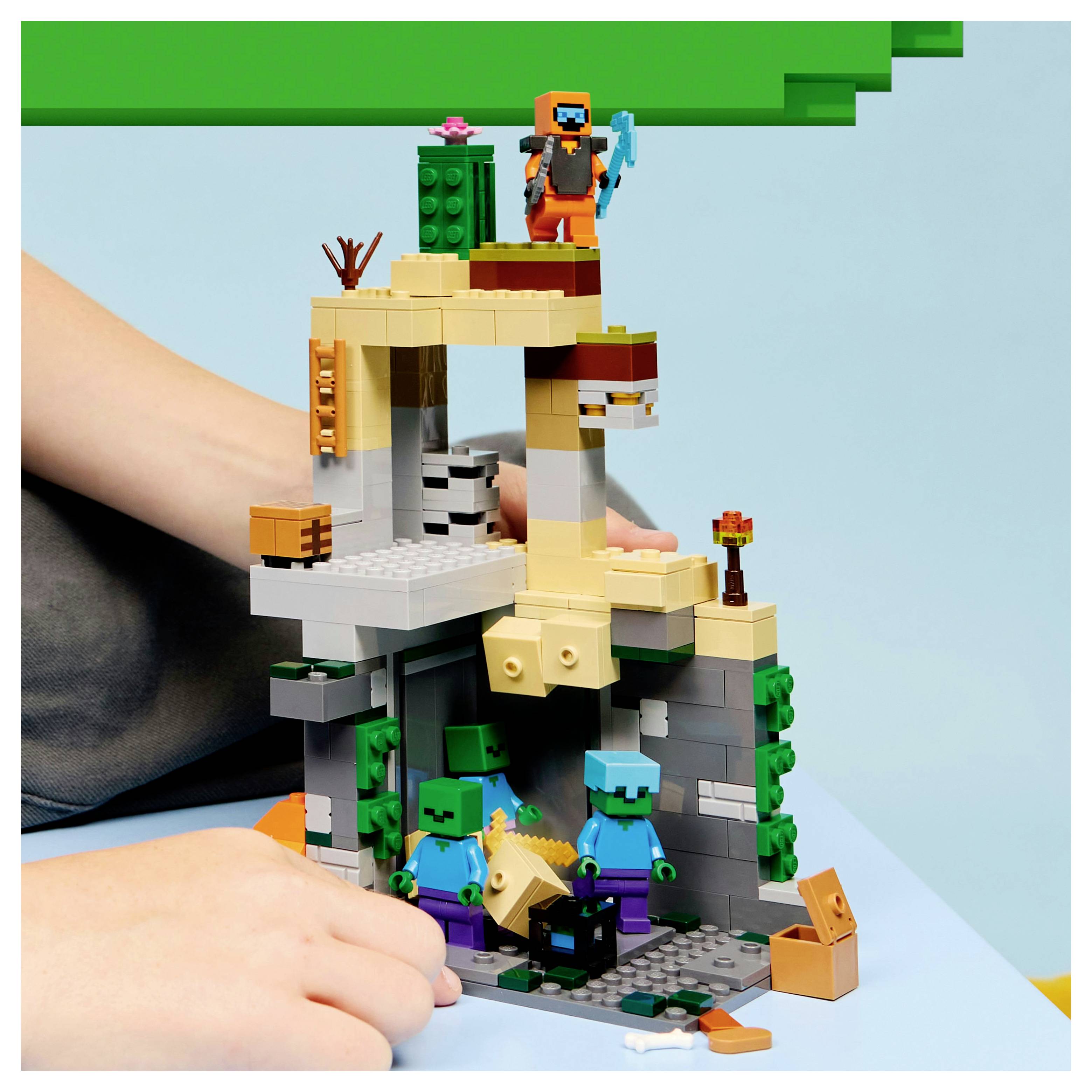 Un enfant construit une scène avec des briques de jouet représentant un personnage tenant un outil au sommet d'une structure, avec deux figures cubiques en dessous.