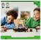 Deux enfants souriant tout en jouant avec un ensemble LEGO sur le thème de Minecraft, avec une créature aux formes cubiques, dans un décor intérieur neutre.