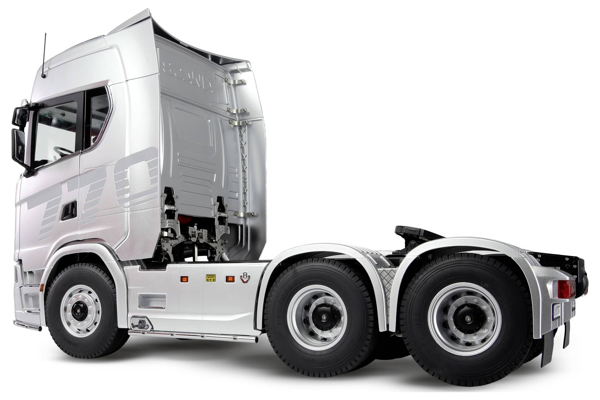 Un tracteur semi-remorque argenté et robuste avec six roues, vu de profil. La remorque est absente, laissant voir les roues arrière et la cabine.