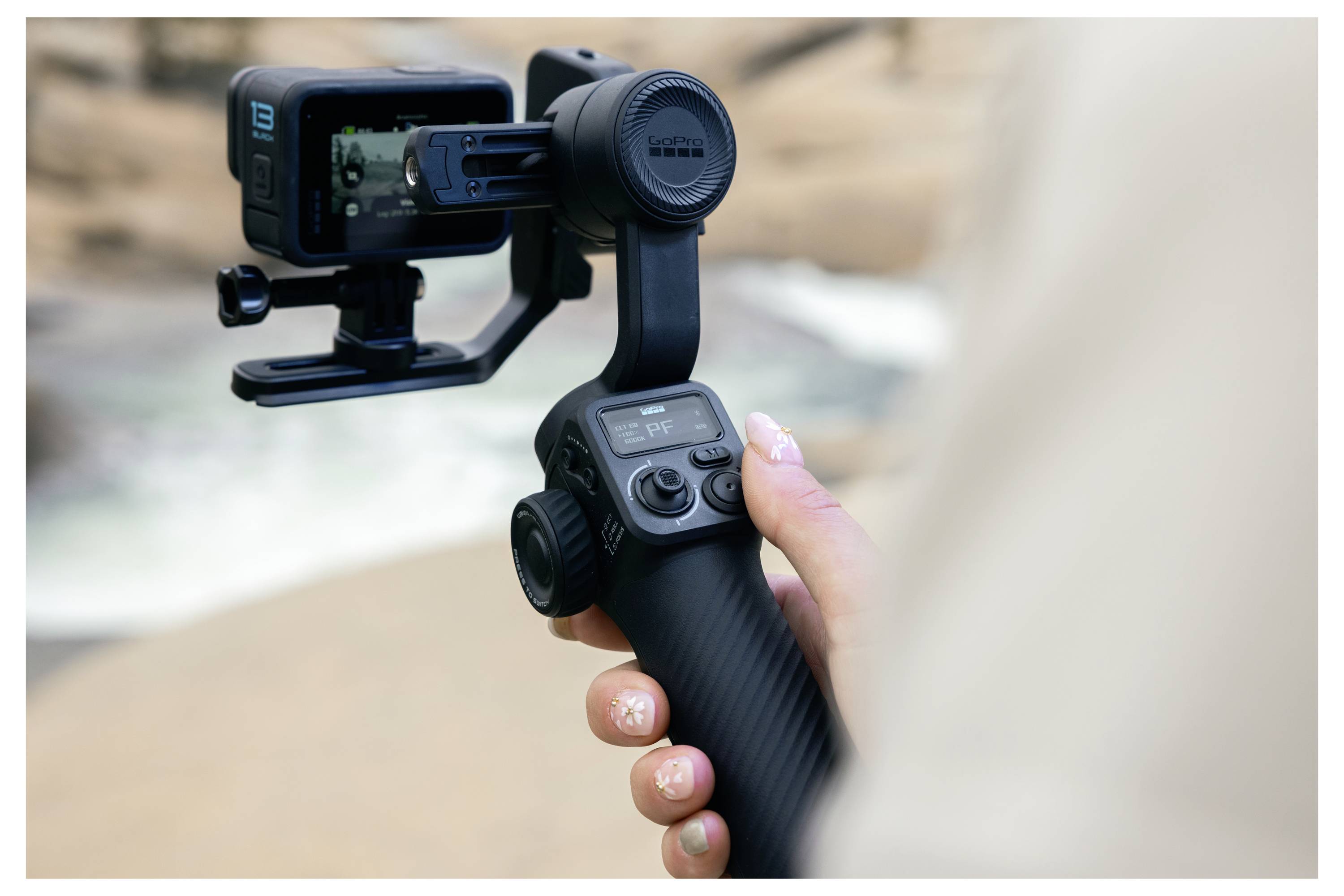 Une personne tient un stabilisateur de caméra avec une caméra d'action montée, capturant des images avec un arrière-plan extérieur flou.