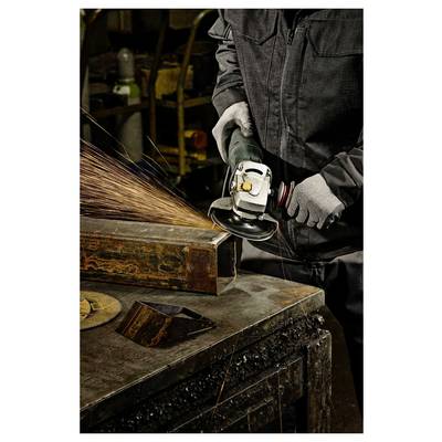 Une personne portant des gants et des vêtements de protection utilise une meuleuse d'angle sur une poutre métallique, provoquant des étincelles dans un environnement d'atelier.