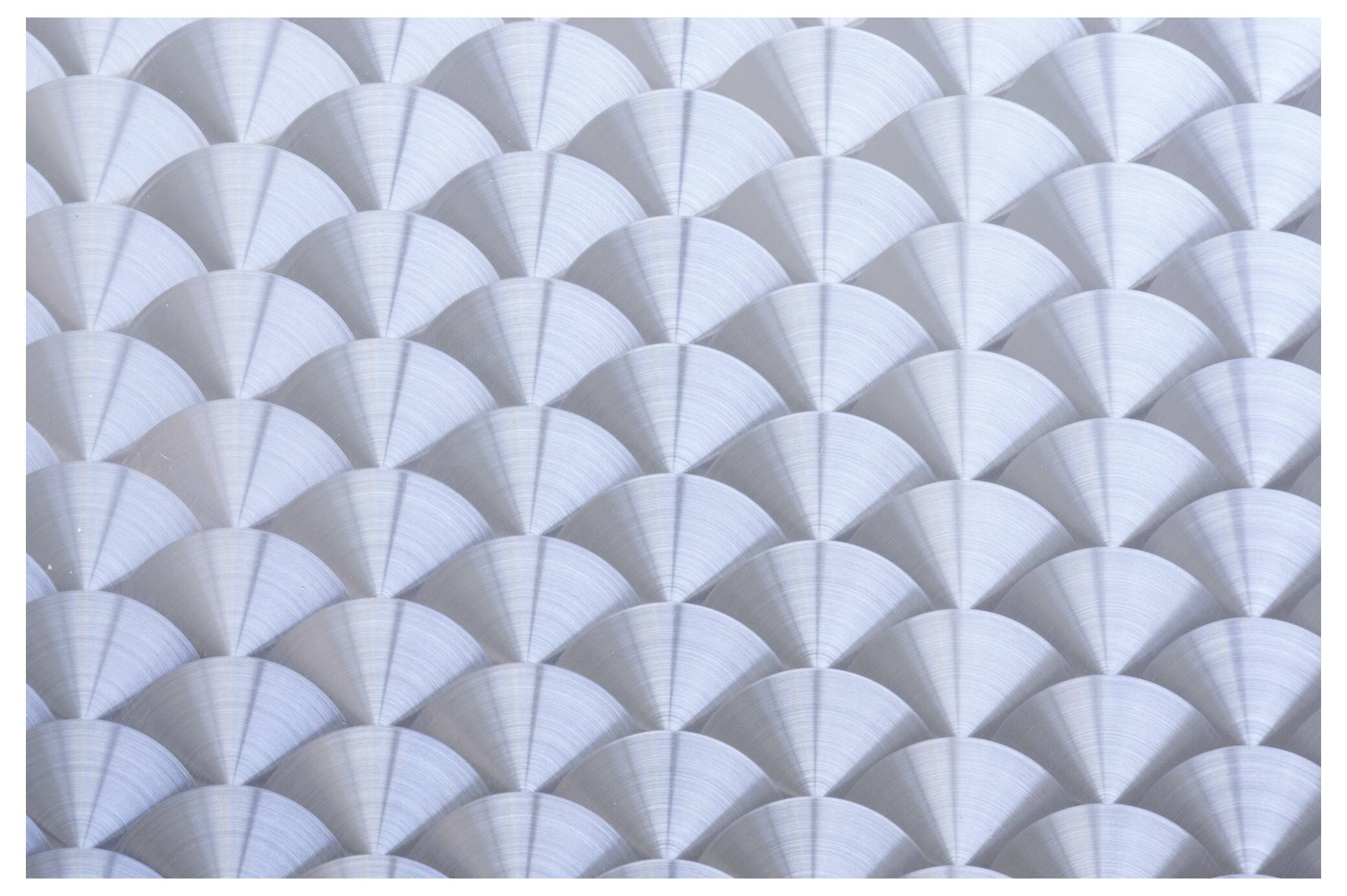 L'image montre un motif de formes de ventilateurs métalliques qui se chevauchent, créant une surface géométrique et texturée.
