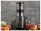 Un presse-fruits noir contenant des fruits à l'intérieur, entouré d'une variété de fruits frais et d'un verre de jus, sur un fond gris.
