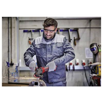 Un travailleur portant des lunettes de protection et des gants utilise une meuleuse d'angle sur du métal dans un atelier. Des étincelles sont visibles pendant le processus de meulage.