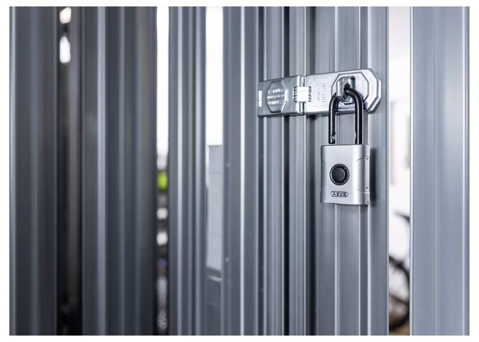 Un cadenas métallique sécurise un loquet sur des panneaux de métal ondulé gris, symbolisant la sécurité et la protection.