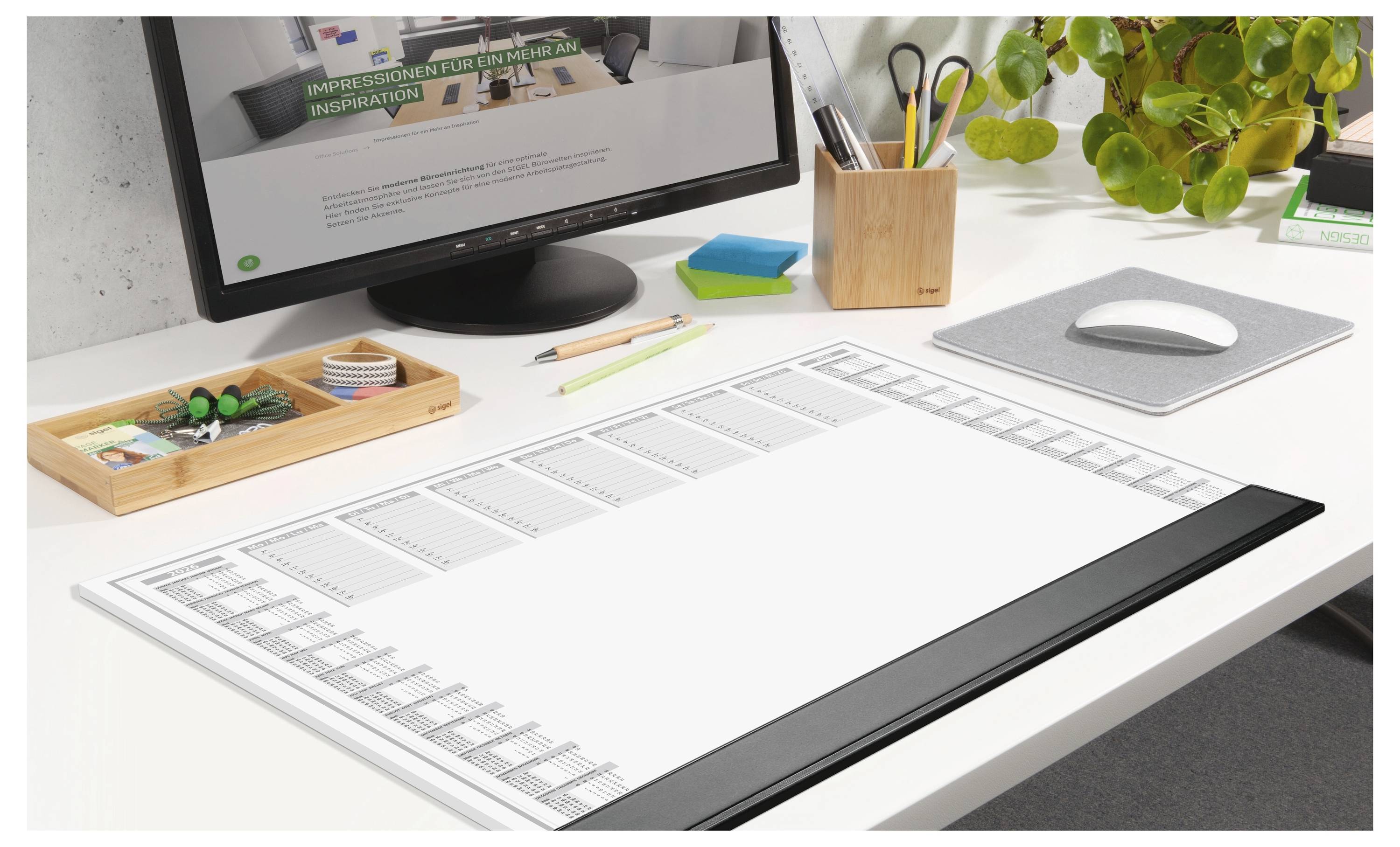 Un bureau propre et organisé avec un ordinateur, un agenda, un plateau à papeterie et une plante en pot, suggérant un espace de travail dédié à la planification ou à la créativité.