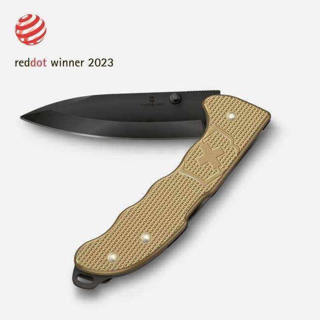 Couteau pliant noir avec manche texturé beige, étiqueté « reddot winner 2023 ».