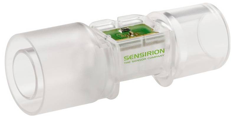 Un capteur de débit médical transparent avec des composants électroniques internes visibles, portant l'étiquette « Sensirion The Sensor Company », utilisé pour mesurer le débit d'air.