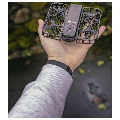 Une main tenant un petit drone noir carré étiqueté 'HOVER' avec des protections autour des hélices.