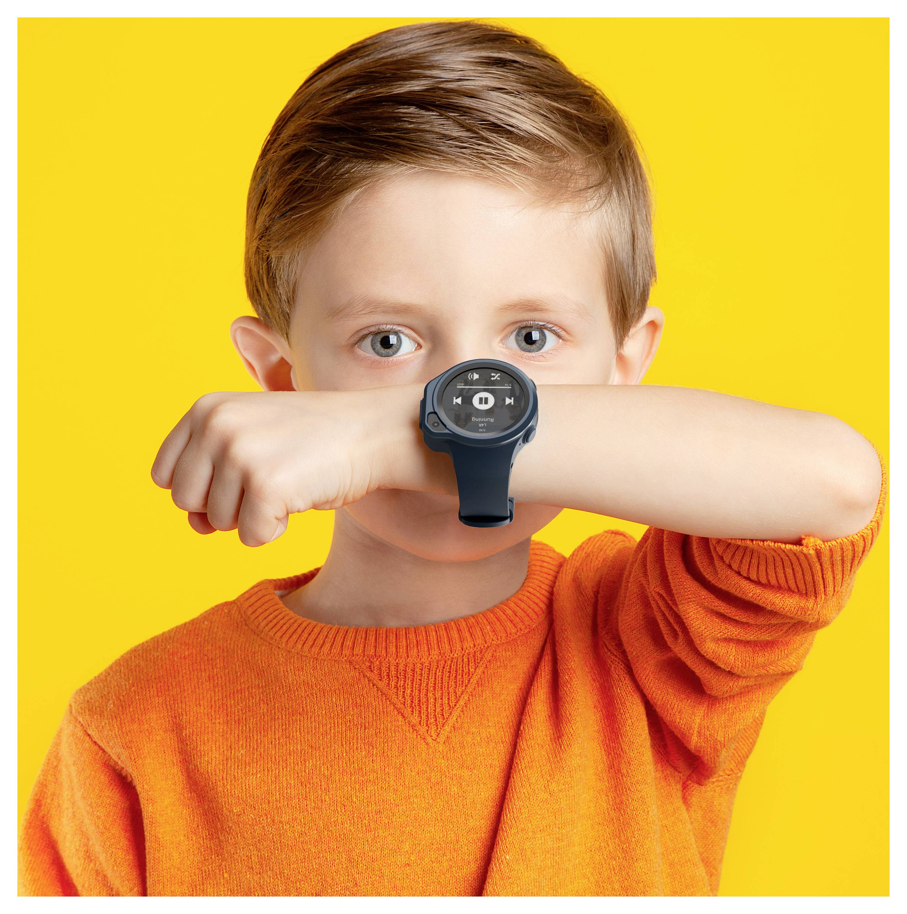 Un jeune enfant portant un t-shirt orange lève son poignet, arborant une montre connectée devant un fond jaune vif.