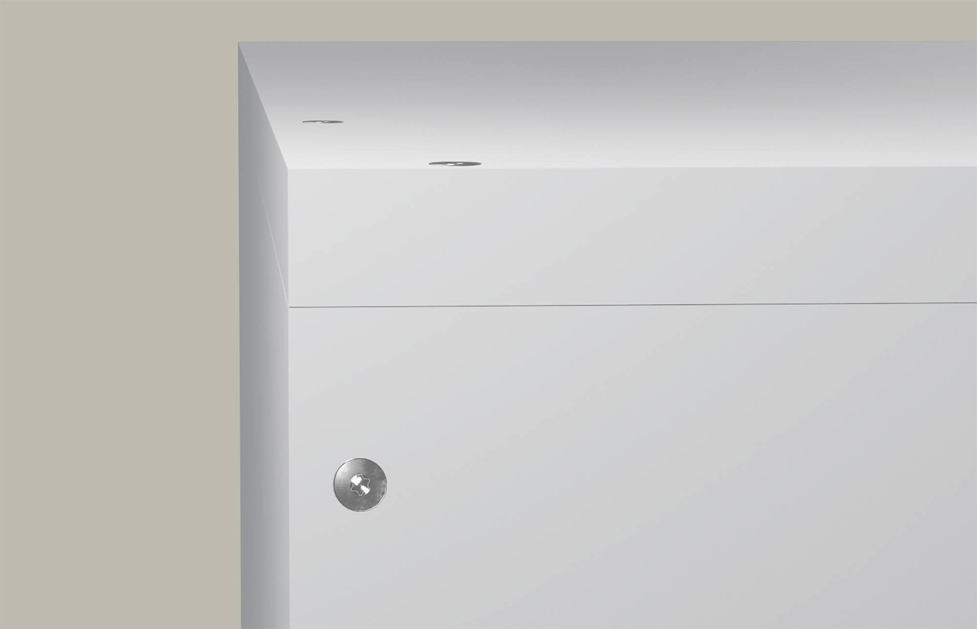 Gros plan d'une armoire blanche ou d'un tiroir avec une poignée en métal rond et deux petits trous de vis visibles sur le bord supérieur.