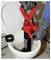 Des mains gantées utilisent un déboucheur rouge pour déboucher une toilette dont le couvercle est ouvert.
