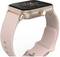 'Une montre connectée avec un boîtier en or rose et un bracelet rose, affichant un cadran analogique avec des aiguilles dorées et des chiffres marqueurs.'